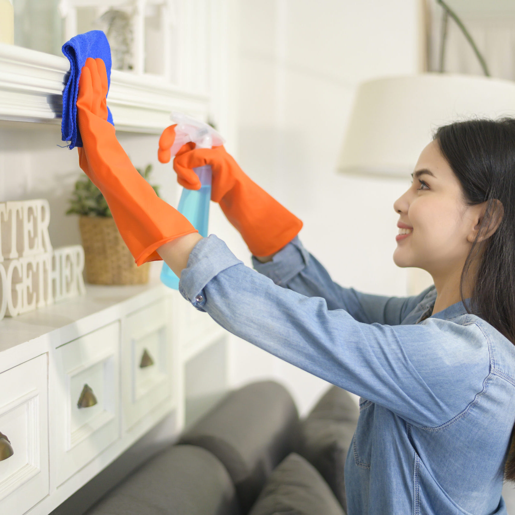 A woman with cleaning gloves using alcohol spray sanitiser to cleaning house, healthy and medical, covid-19 protection at home concept .