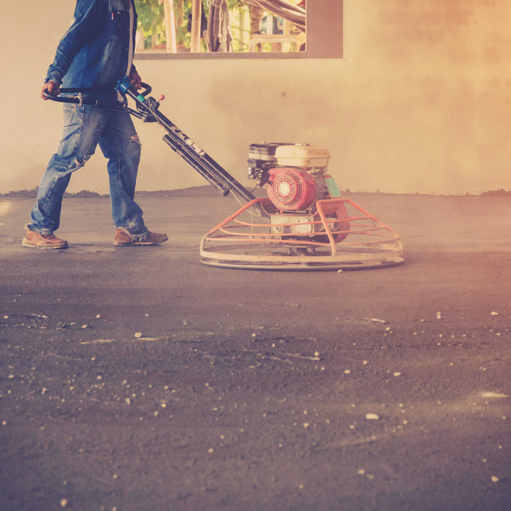 Plasterer working using scrubber machine for cement floor with vintage toned