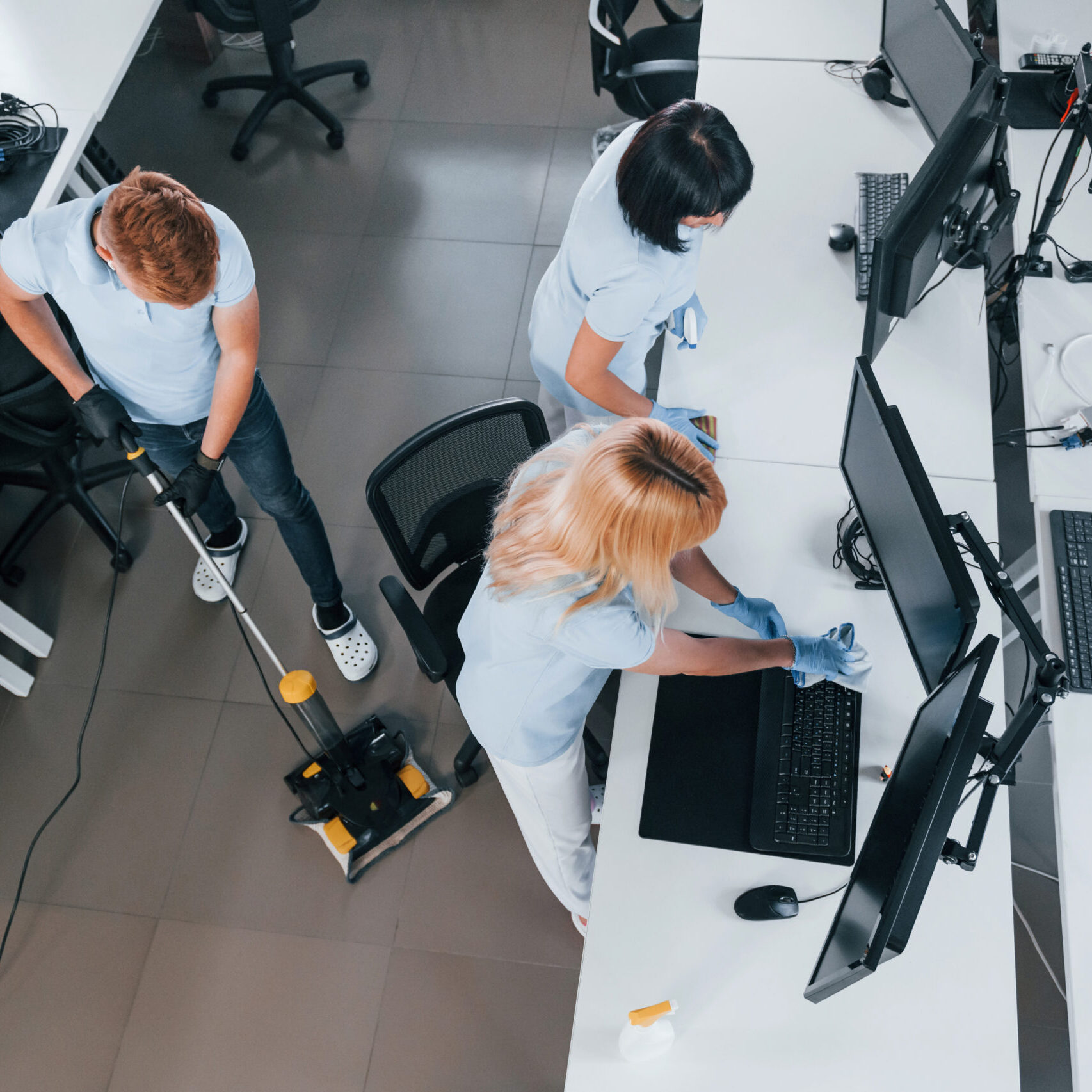 Top view. Group of workers clean modern office together at daytime.