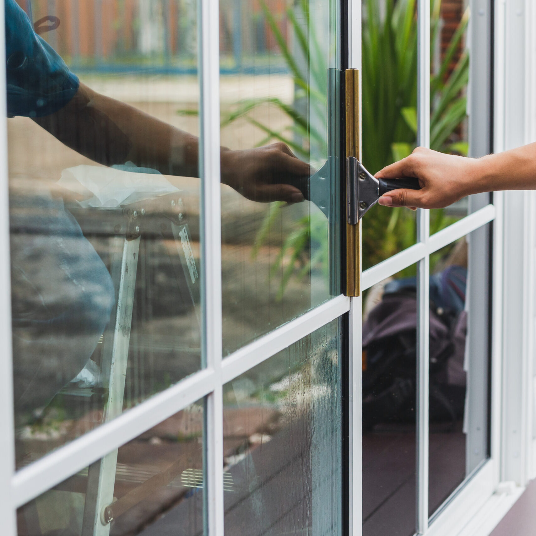 Worker use scraper cleaning window before installing tinting film